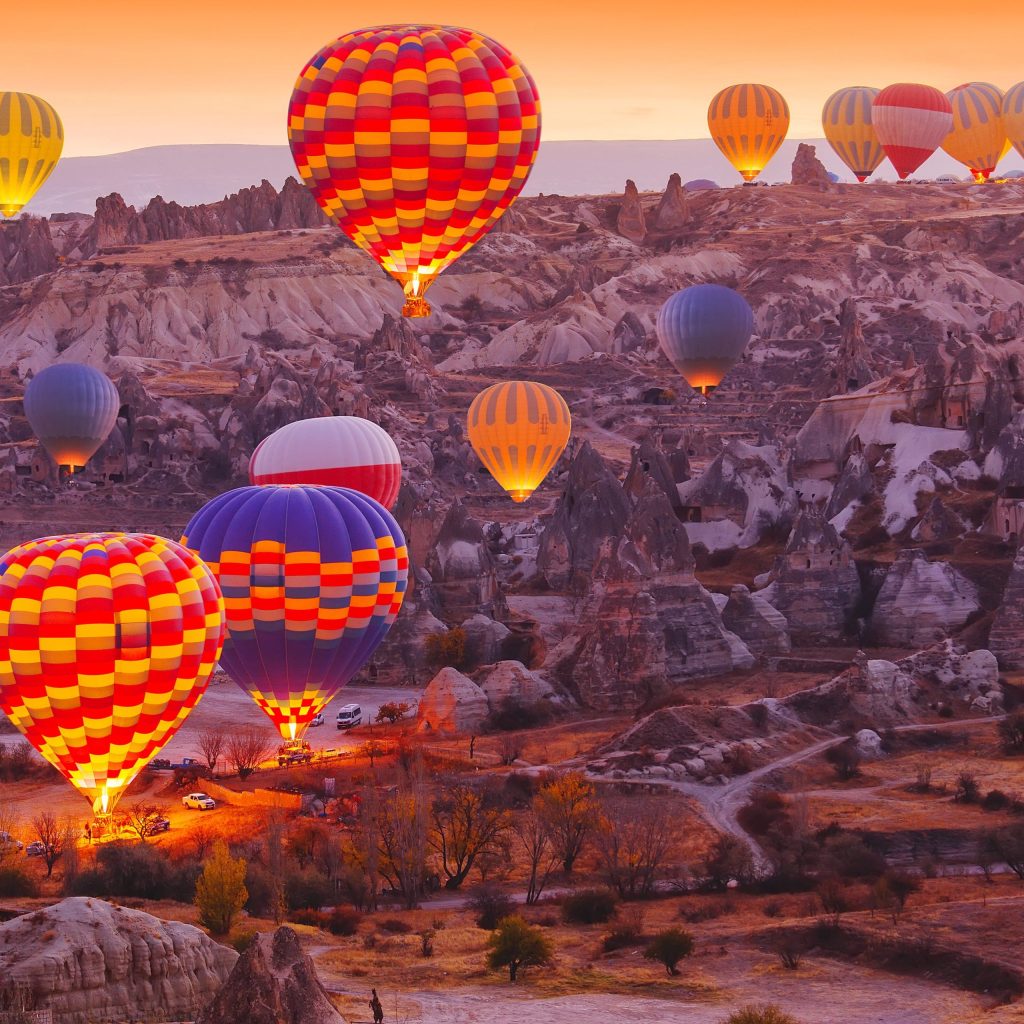 Colorful hot air balloons flying over the fairy chimneys of Cappadocia at sunrise.
