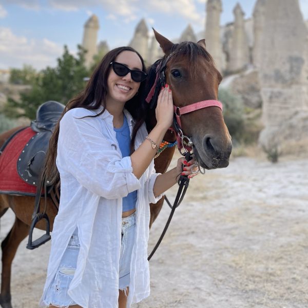 Cappadocia Horseback Riding Tour Tourists riding horses through the scenic valleys of Cappadocia during sunset.