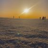 A couple walking on the reflective white surface of Salt Lake during sunset, creating a dreamy mirrored scene.